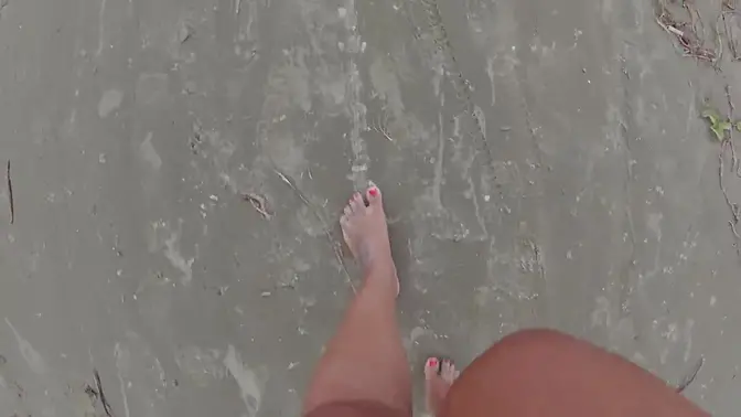 Sultry woman walks barefoot on beach and street