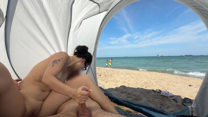 My Asian GF sits on a public beach, jerking my cock while I'm naked.